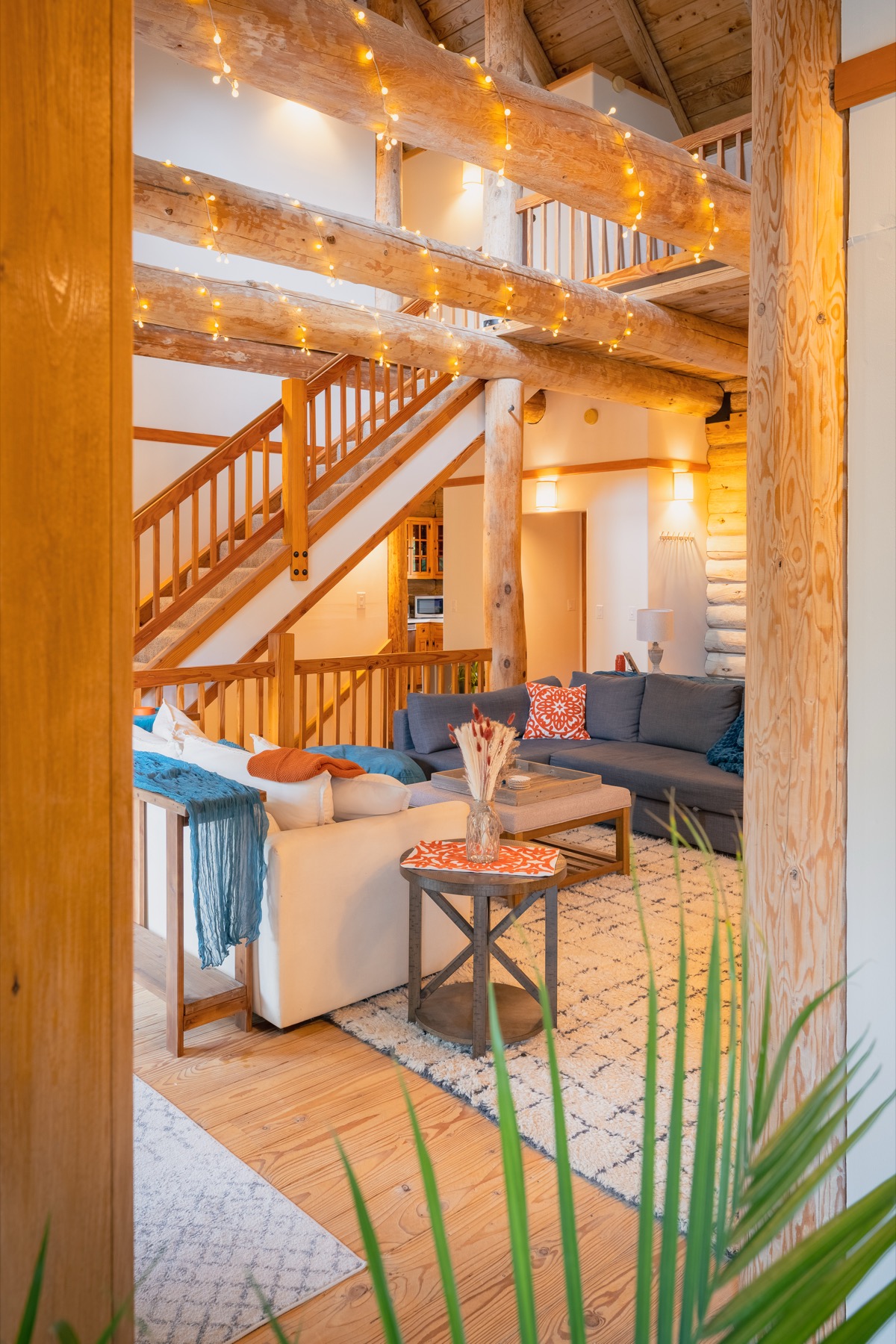 Warm great room view framed by timber beams and string lights