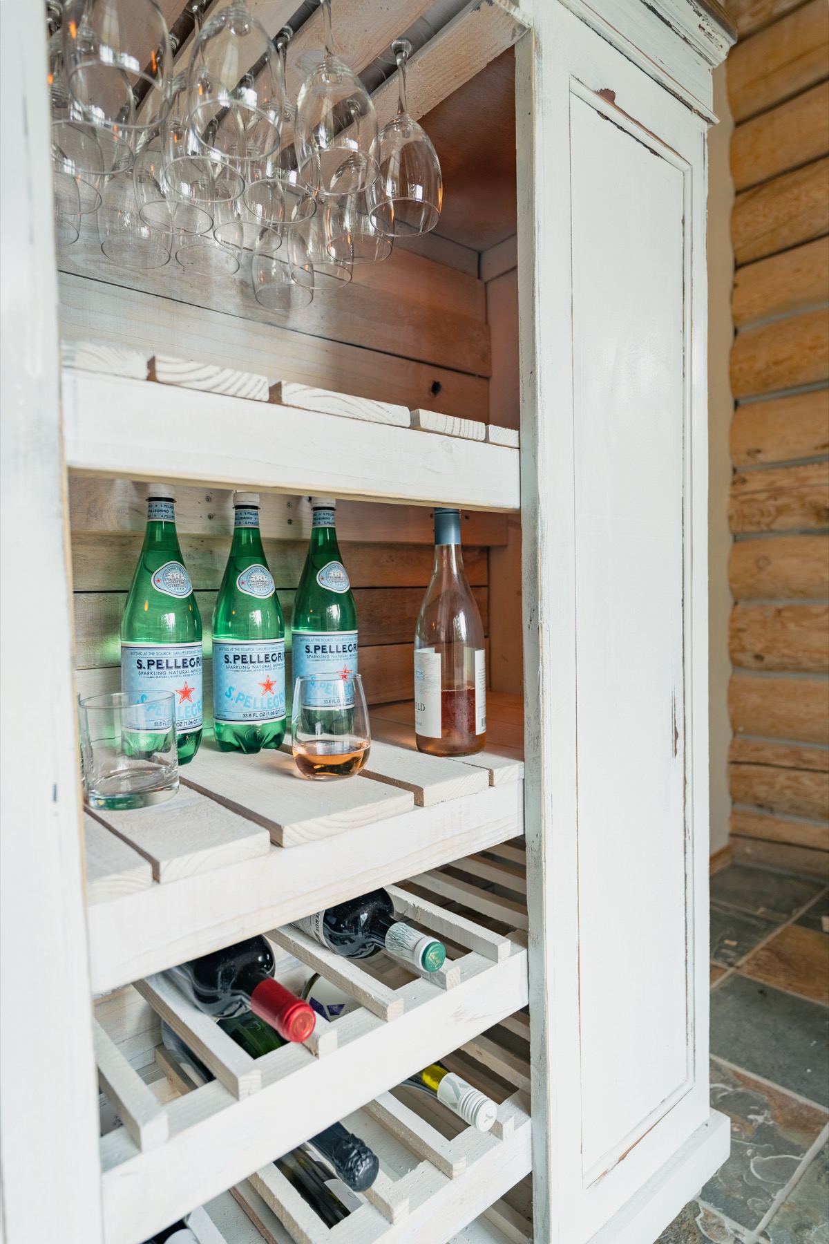 Cabinet stocked with glassware, sparkling water, and bottles